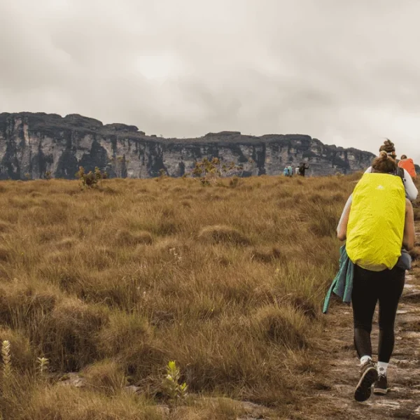 Mulheres caminham pelo Vale do Pati, Gerais do rio Preto, com montanhas e vegetação verde ao fundo.