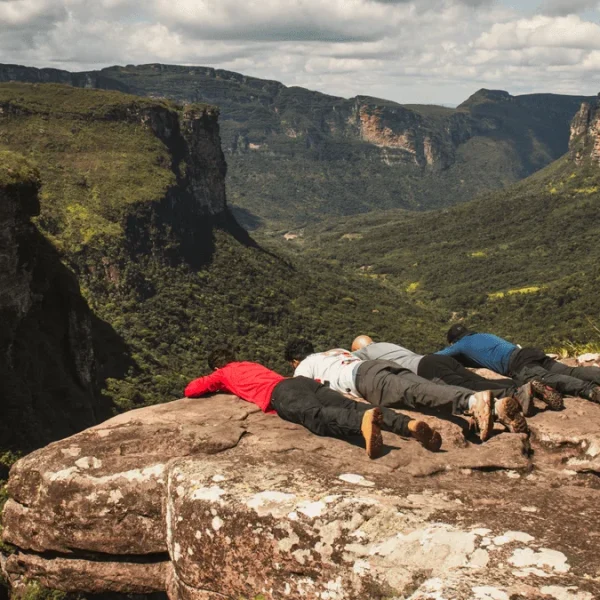 Grupo de trilheiros se esgueira para visualizar mirante no Trekking do Vale do Pati com Fumacinha e Buracão.