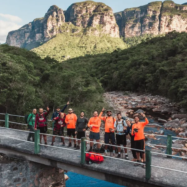 Pessoas caminhando pelo Vale do Pati, com destaque para as serras de Andaraí ao fundo da fotografia.