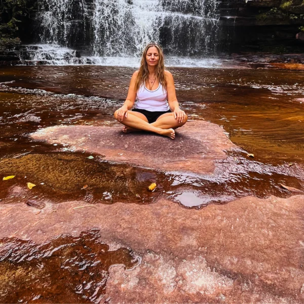 Mulher toma banho de Cachoeira enquanto medita no rio Funis, Chapada Diamantina.